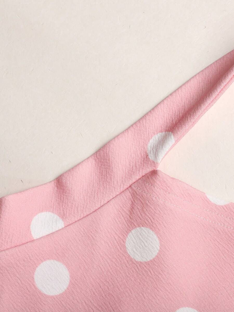 Black sleeveless halter polka dot mini dress for tween girls featuring a high waist and flared hem