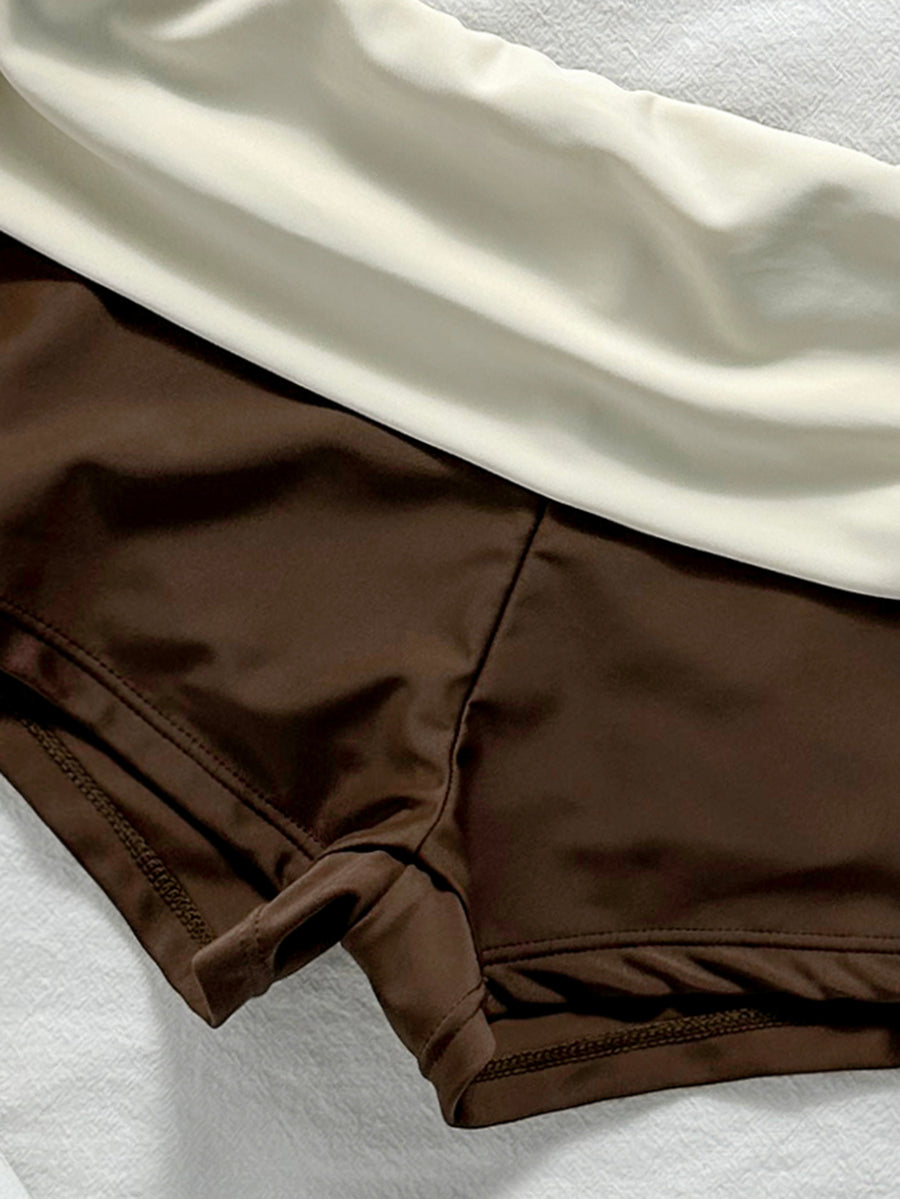Women's halter triangle bikini top with knot detail paired with mid-waist colorblock swim shorts.
