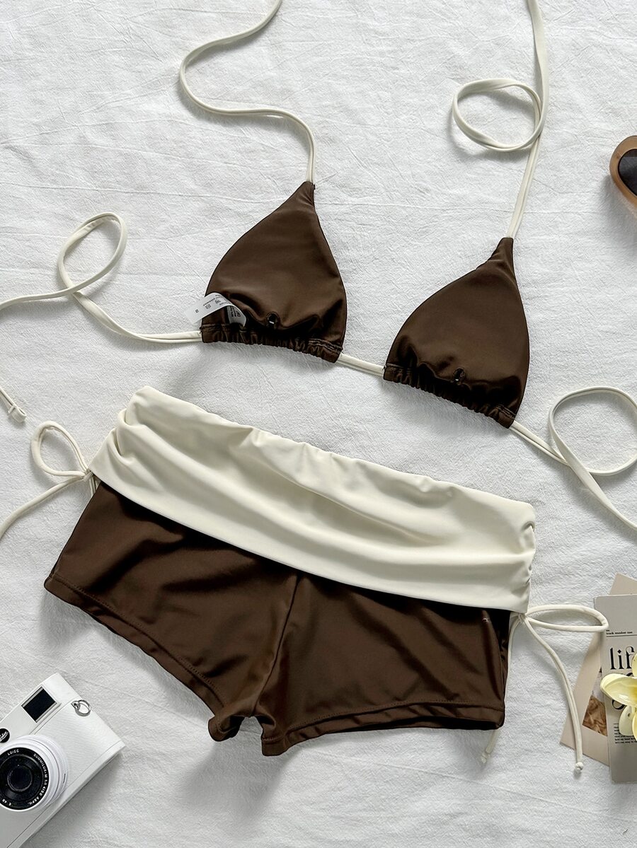 Women's halter triangle bikini top with knot detail paired with mid-waist colorblock swim shorts.