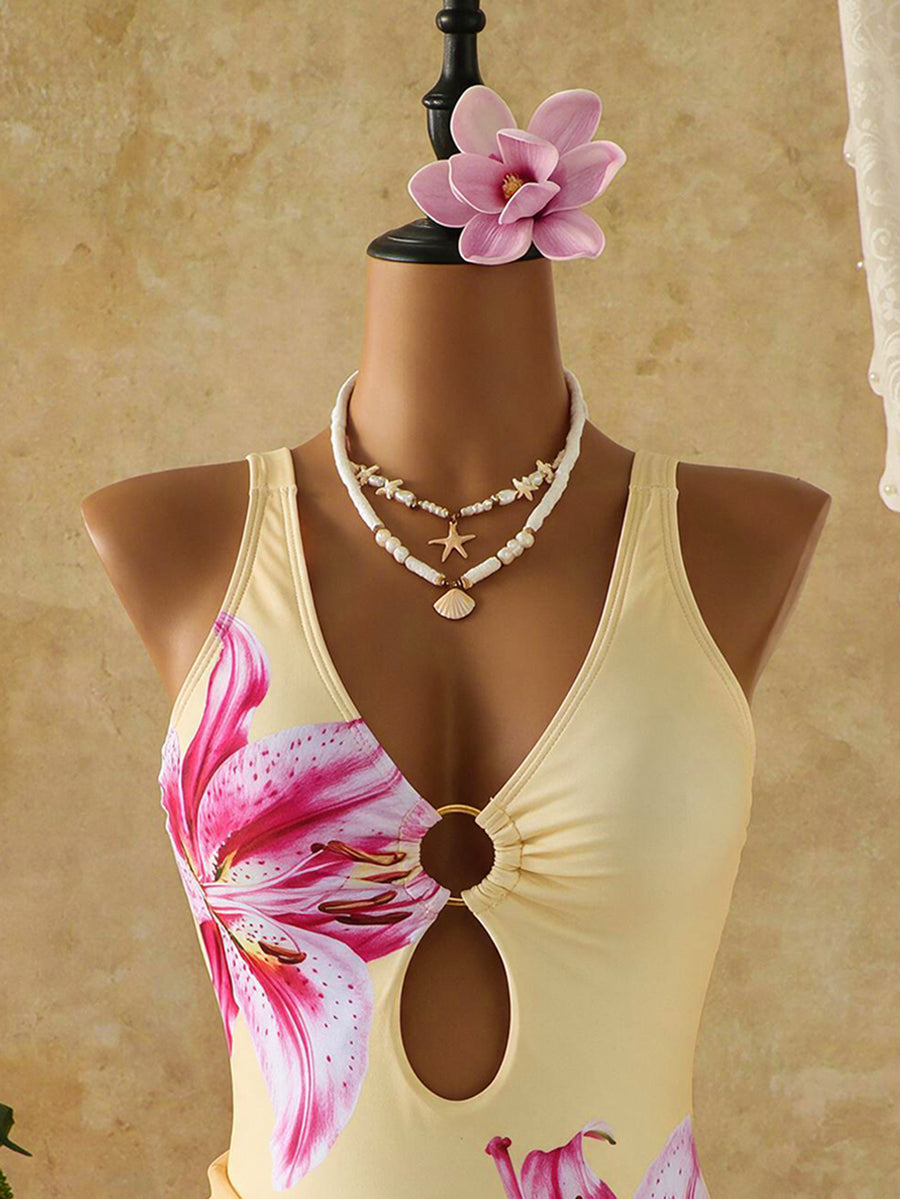 Women's black floral print plunge neck one-piece swimsuit featuring cut-out detail paired with a matching knee-length mesh cover-up skirt